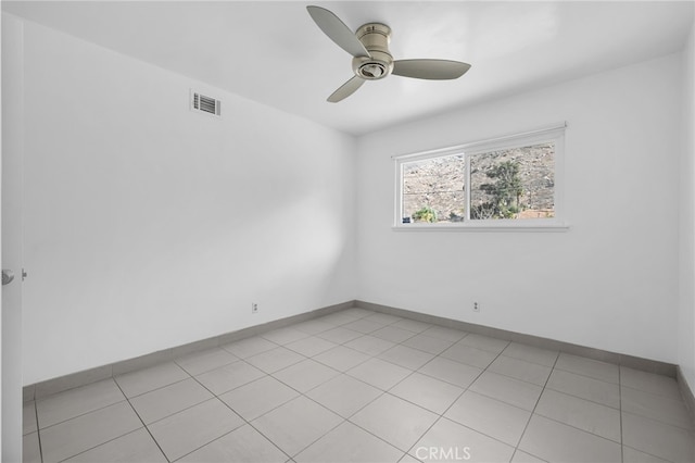 spare room with a ceiling fan, visible vents, baseboards, and light tile patterned floors