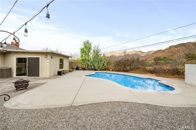 view of pool featuring an outdoor fire pit, a patio area, a mountain view, and fence