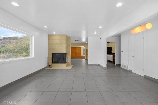 unfurnished living room with tile patterned flooring, recessed lighting, visible vents, baseboards, and a brick fireplace