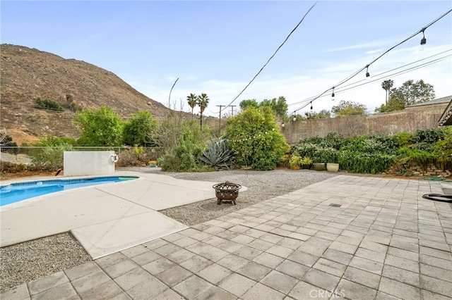 view of patio featuring fence private yard, an outdoor fire pit, a mountain view, and a fenced in pool