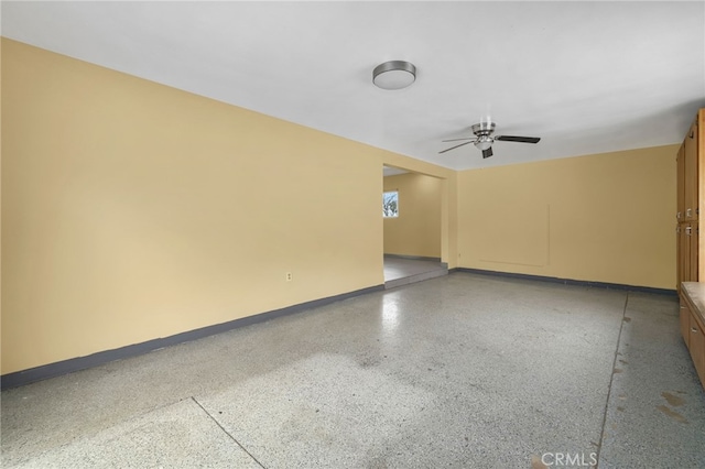 unfurnished room featuring a ceiling fan, baseboards, and speckled floor