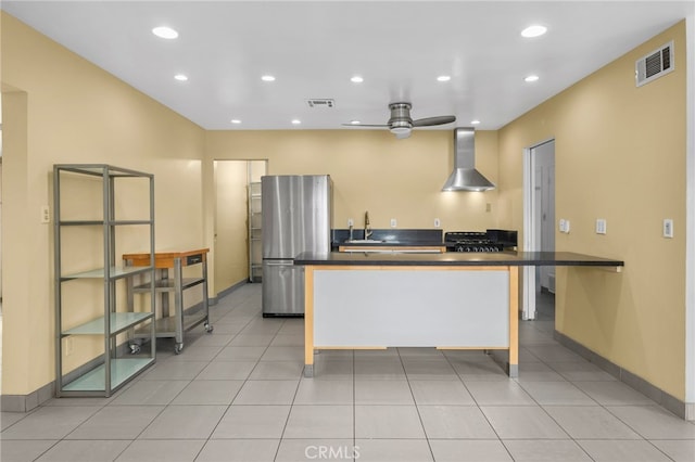 kitchen with visible vents, wall chimney range hood, dark countertops, and freestanding refrigerator