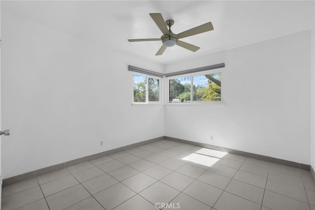 unfurnished room featuring a ceiling fan, light tile patterned flooring, and baseboards