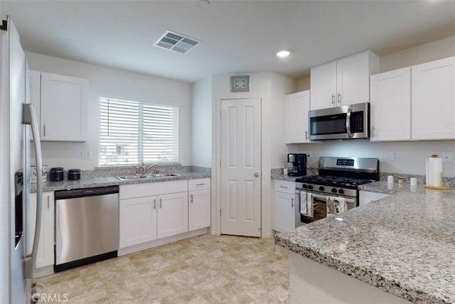 kitchen with a sink, visible vents, white cabinets, and appliances with stainless steel finishes
