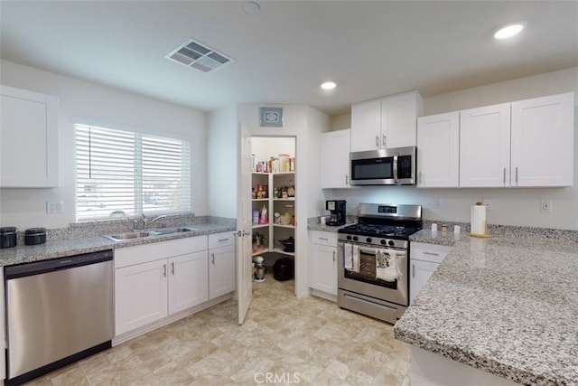 kitchen with stainless steel appliances, visible vents, white cabinets, and a sink