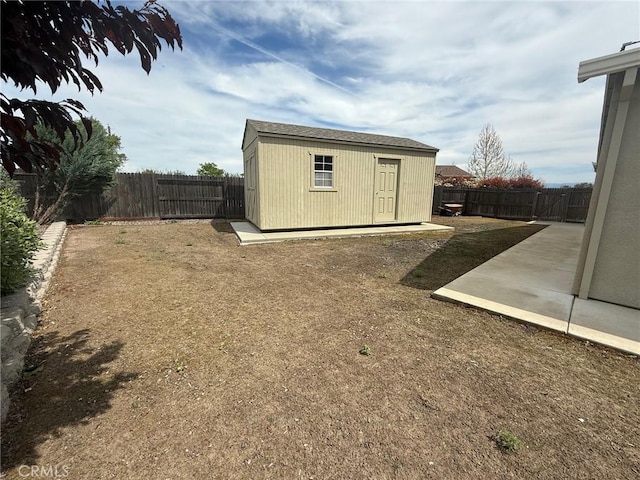 view of yard with a storage shed, a patio area, a fenced backyard, and an outdoor structure