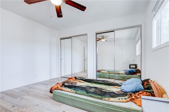 bedroom with two closets, ceiling fan, and hardwood / wood-style flooring