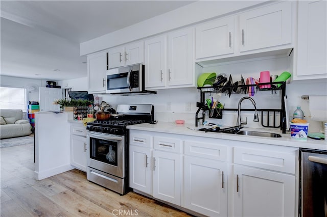 kitchen featuring white cabinetry, sink, light hardwood / wood-style flooring, and appliances with stainless steel finishes