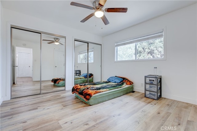 bedroom with multiple closets, ceiling fan, and light hardwood / wood-style floors