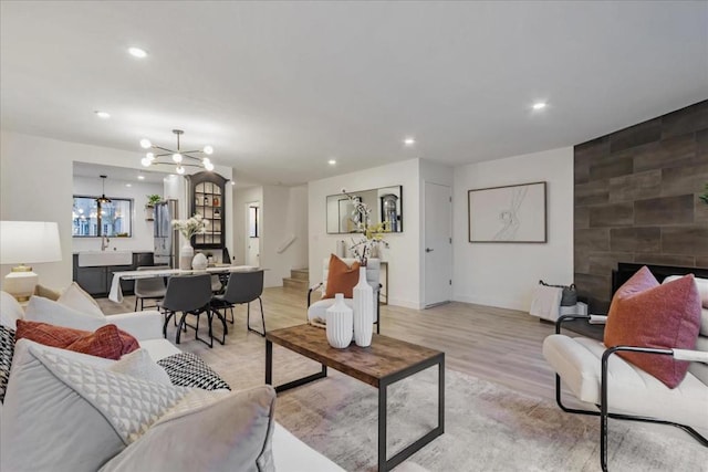 living room with sink, a fireplace, a chandelier, and light hardwood / wood-style floors