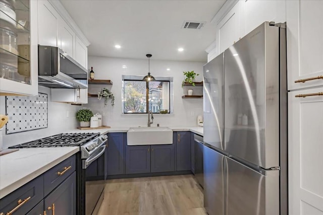 kitchen with white cabinetry, stainless steel appliances, sink, and hanging light fixtures