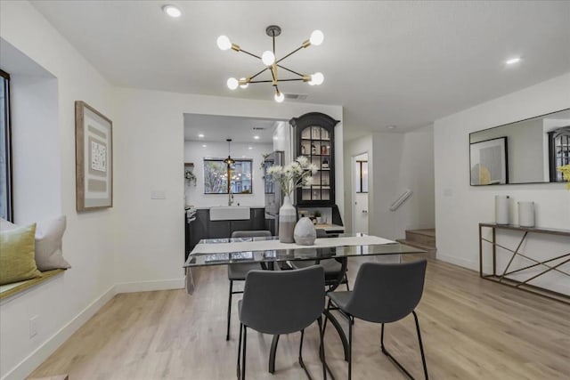 dining space featuring sink, light hardwood / wood-style floors, and a chandelier