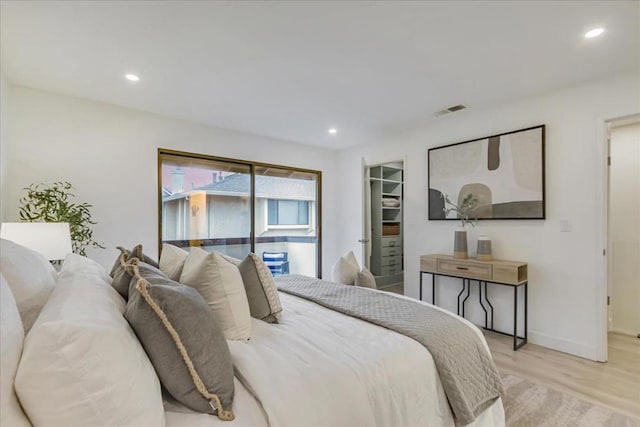 bedroom featuring a walk in closet and light hardwood / wood-style floors