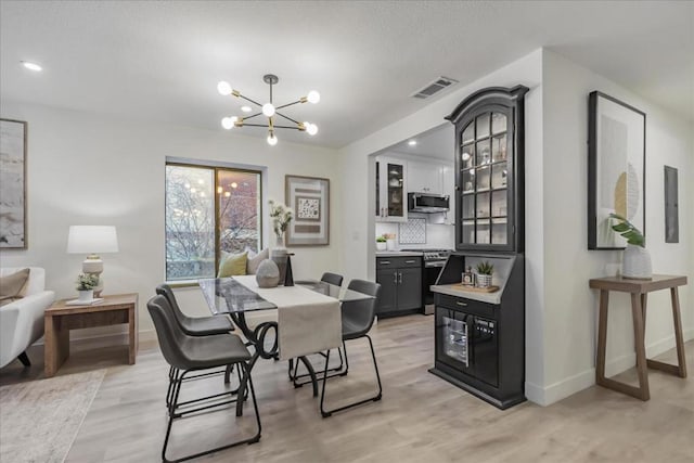 dining room featuring electric panel, a chandelier, and light hardwood / wood-style floors