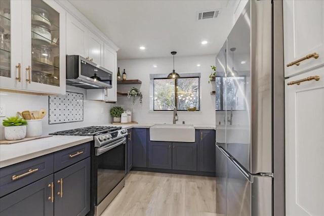 kitchen featuring appliances with stainless steel finishes, decorative light fixtures, sink, white cabinets, and backsplash