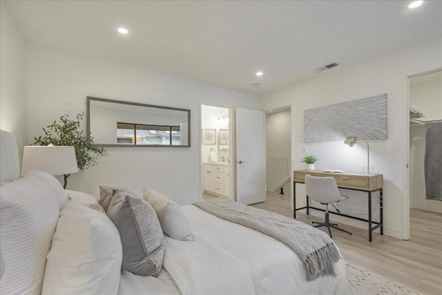 bedroom with connected bathroom, a spacious closet, and light hardwood / wood-style flooring