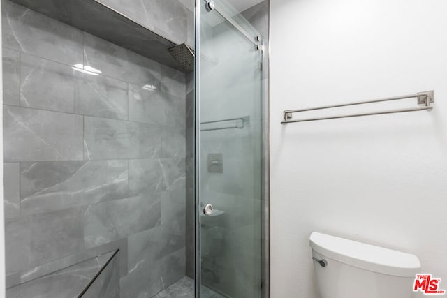 bathroom featuring toilet and a shower with shower door