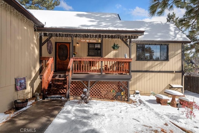 snow covered rear of property featuring covered porch