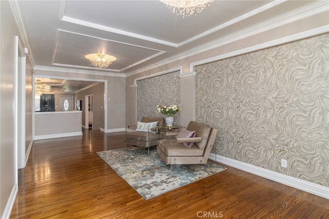 sitting room with hardwood / wood-style floors, ornamental molding, and a chandelier