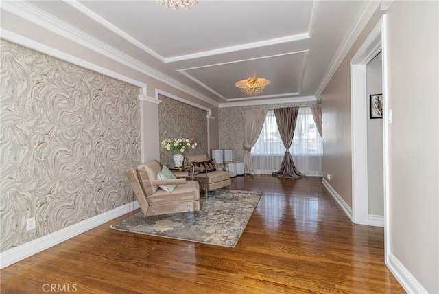 living area featuring wallpapered walls, crown molding, baseboards, and wood finished floors