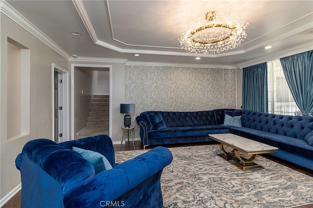 living room with ornamental molding, hardwood / wood-style floors, a notable chandelier, and a tray ceiling