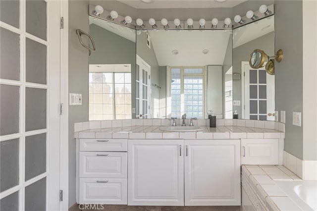 bathroom featuring a bath, visible vents, lofted ceiling, and vanity