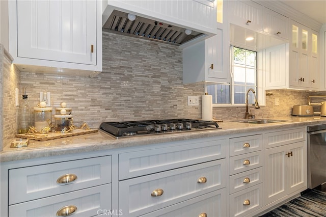 kitchen featuring range hood, stainless steel appliances, glass insert cabinets, white cabinetry, and a sink