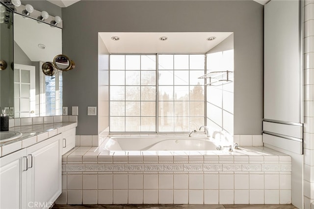 bathroom with a relaxing tiled tub and vanity