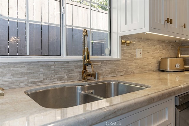 details with sink, light stone counters, dishwasher, decorative backsplash, and white cabinets