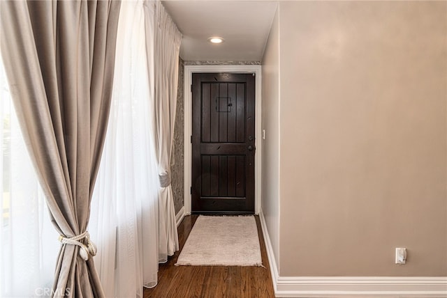 hallway with dark wood-type flooring and baseboards