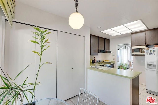 kitchen featuring white appliances, hanging light fixtures, dark brown cabinetry, kitchen peninsula, and exhaust hood