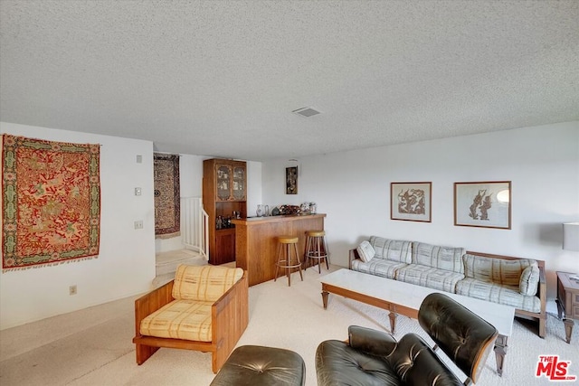 carpeted living room featuring bar area and a textured ceiling