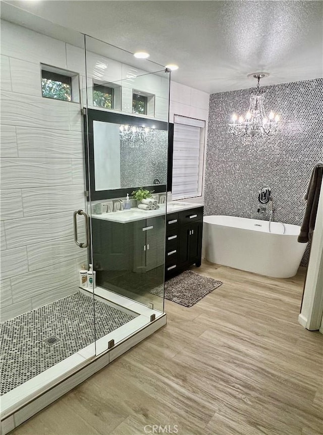 bathroom featuring wood-type flooring, a textured ceiling, vanity, independent shower and bath, and a notable chandelier