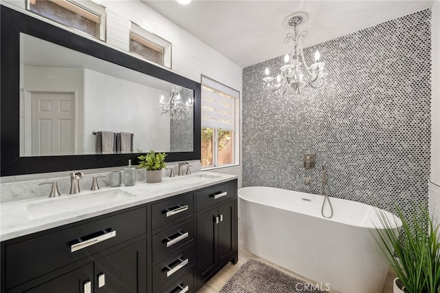 bathroom with a tub to relax in, vanity, tile walls, and a notable chandelier