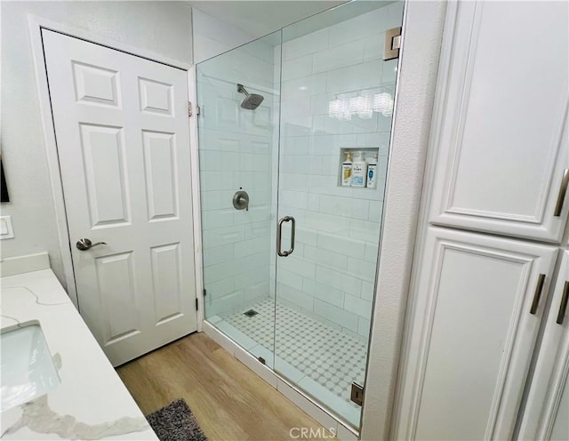 bathroom featuring hardwood / wood-style flooring, vanity, and a shower with door