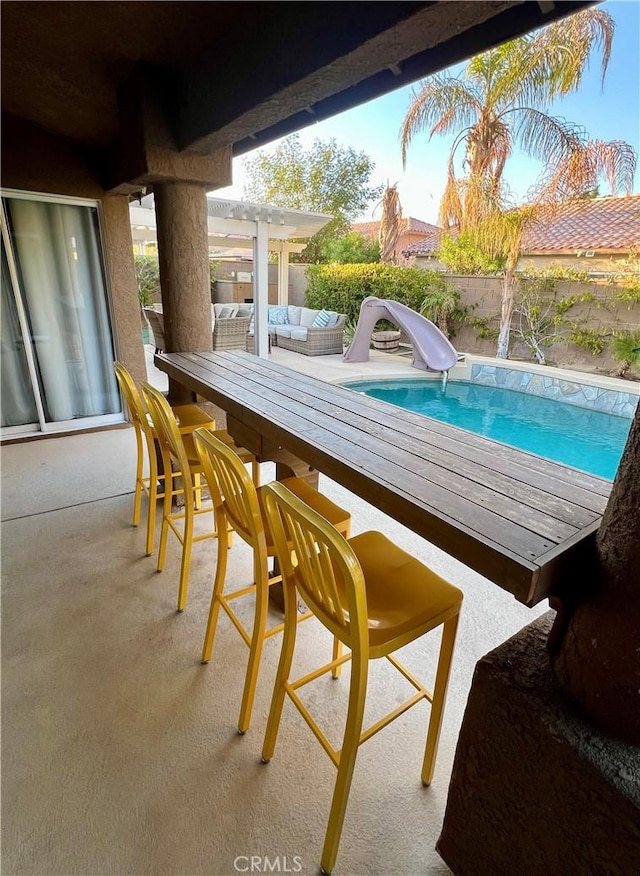 view of swimming pool with an outdoor living space, a pergola, and a water slide