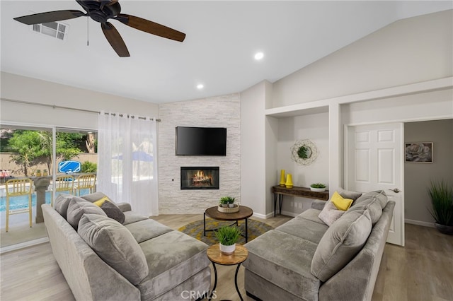 living room featuring vaulted ceiling, a fireplace, and light wood-type flooring