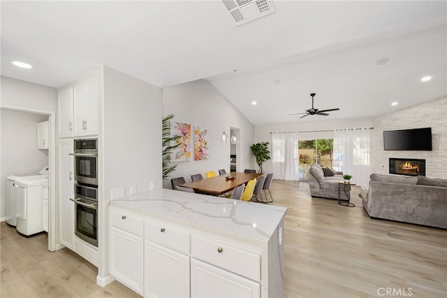 kitchen featuring washer and clothes dryer, light stone countertops, light hardwood / wood-style floors, and white cabinets