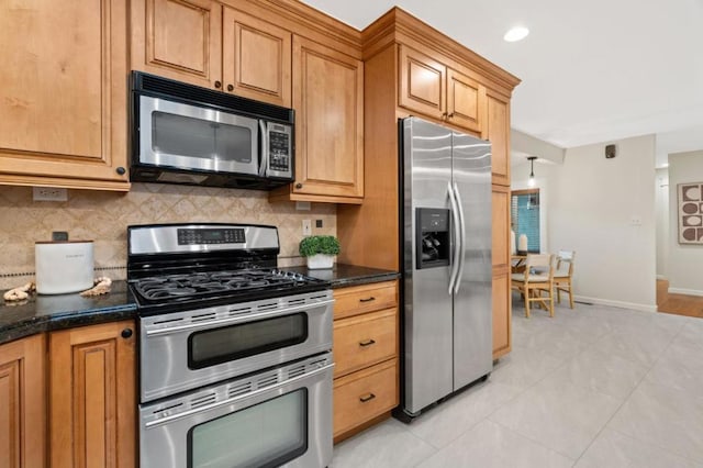 kitchen with tasteful backsplash, appliances with stainless steel finishes, dark stone counters, and light tile patterned floors