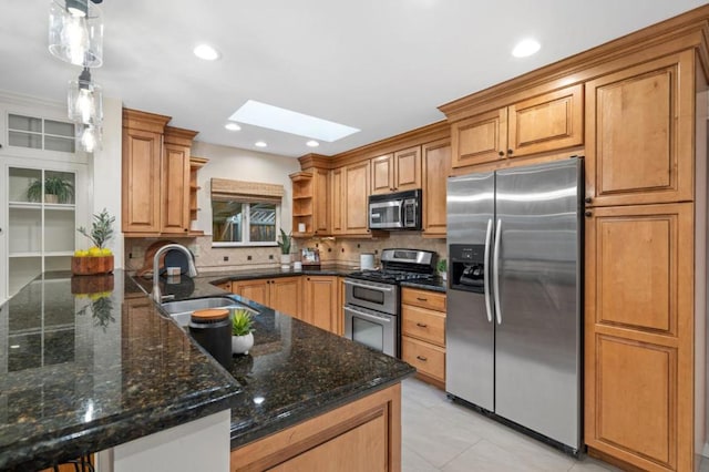 kitchen featuring sink, a skylight, kitchen peninsula, pendant lighting, and stainless steel appliances