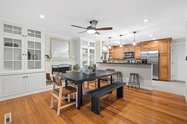 dining space featuring ceiling fan, ornamental molding, sink, and light wood-type flooring