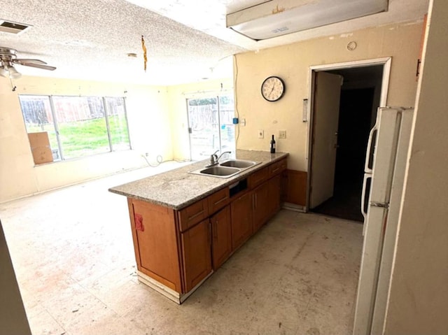 kitchen with sink, kitchen peninsula, a textured ceiling, and white refrigerator