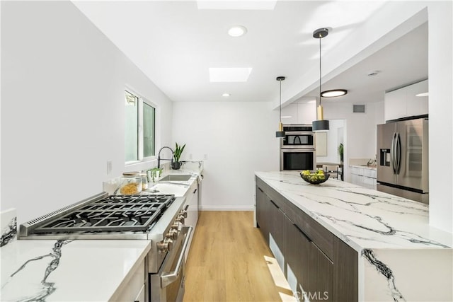 kitchen with dark brown cabinetry, sink, a skylight, appliances with stainless steel finishes, and white cabinets