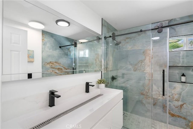 bathroom featuring vanity, plenty of natural light, and a shower with door