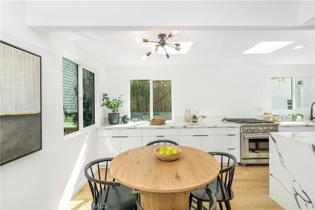 kitchen featuring white cabinetry, high end range, light stone counters, and a wealth of natural light