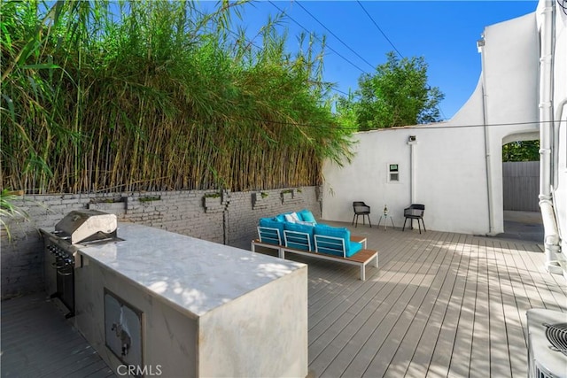 wooden terrace featuring a grill, an outdoor kitchen, and an outdoor hangout area