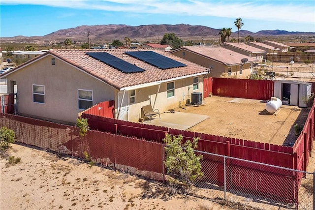 back of house with a mountain view, central AC unit, and solar panels