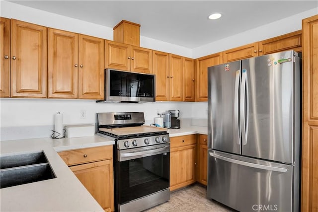 kitchen with appliances with stainless steel finishes, sink, and light tile patterned floors