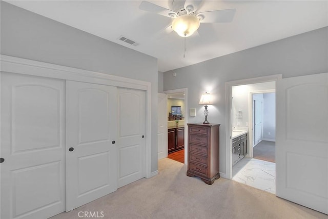 bedroom with light colored carpet, a closet, ceiling fan, and ensuite bathroom