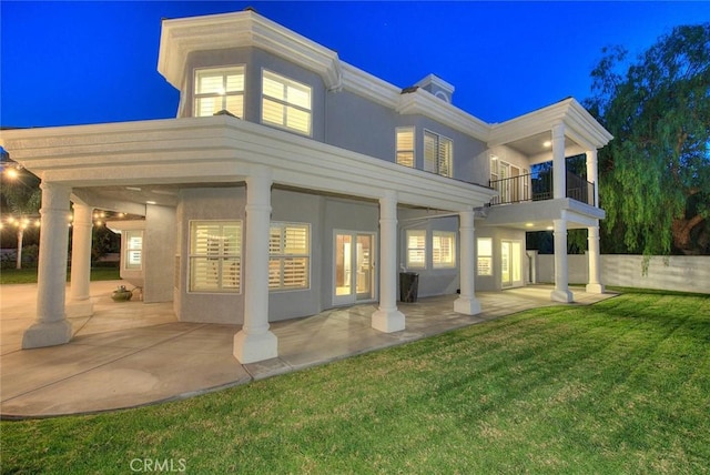 back of property with a lawn, a balcony, and a patio area